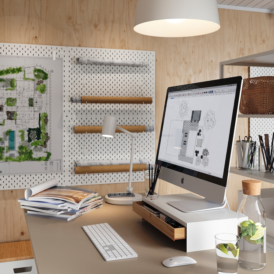 A white monitor stand with a drawer, measuring 10x47x26 cm. Made of durable bamboo with a white aluminum frame, it features compartments for organizing office supplies and a space to store a keyboard. The ergonomic design helps reduce neck and shoulder strain while providing cable management for a tidy workspace.